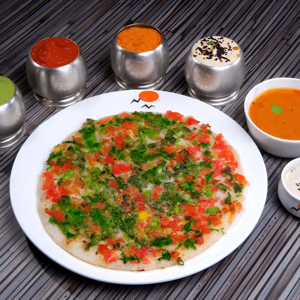 Savory uttapam topped with tomatoes and herbs, served with various chutneys and sambar.